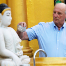Kong Harald heller vann over en statue av Buddah under besøket til Shwedagon-pagoden. Foto: Soe Zeya Tun, Reuters 